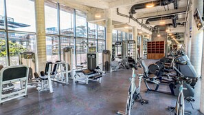 A gym with various exercise equipment, large windows, and a concrete floor. - Tulum 1BR Escape | Private Rooftop Jacuzzi (Tulum)