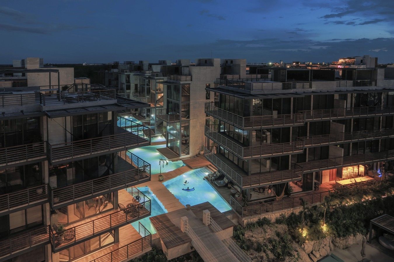 Un immeuble à plusieurs étages doté d’une piscine sur le toit et d’espaces de détente en plein air.