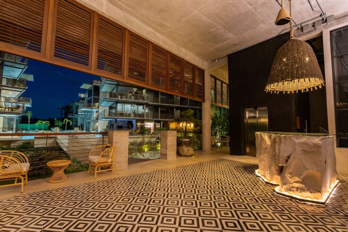 Un espacio exterior moderno con suelo estampado, mobiliario y una gran pieza decorativa.