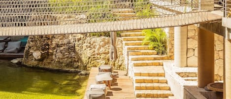 A wooden deck over a body of water with steps leading down to a seating area.