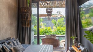 Un dormitorio moderno con una cama grande, vistas a un jardín exuberante y plantas colgantes.
