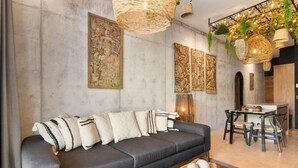 Una sala de estar moderna con un sofá negro, arte decorativo en la pared y un comedor con mesa y sillas.