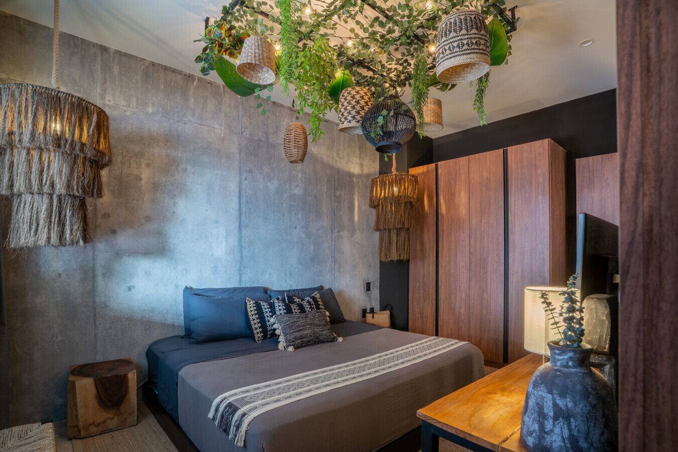 A modern bedroom with a large bed, wooden side tables, and hanging lamps.