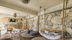 Ein rustikales Interieur mit Steinwänden, Holzdielen und einem Hängestuhl.