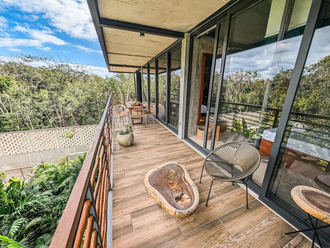 A modern balcony with wooden flooring, a round wooden table, and a chair.