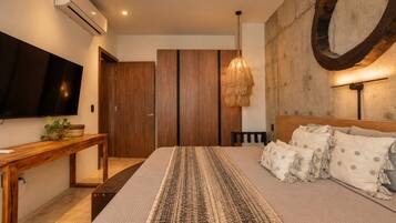 Ein Schlafzimmer mit einem Bett, einem Fernseher, einem Holztisch und einem an der Wand befestigten Spiegel.