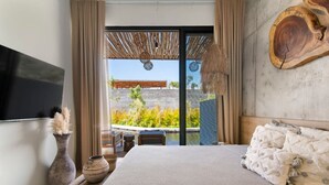 Une chambre moderne dotée d’un grand lit, d’un téléviseur à écran plat, d’une œuvre d’art murale en bois et offrant une vue sur une piscine et un jardin.