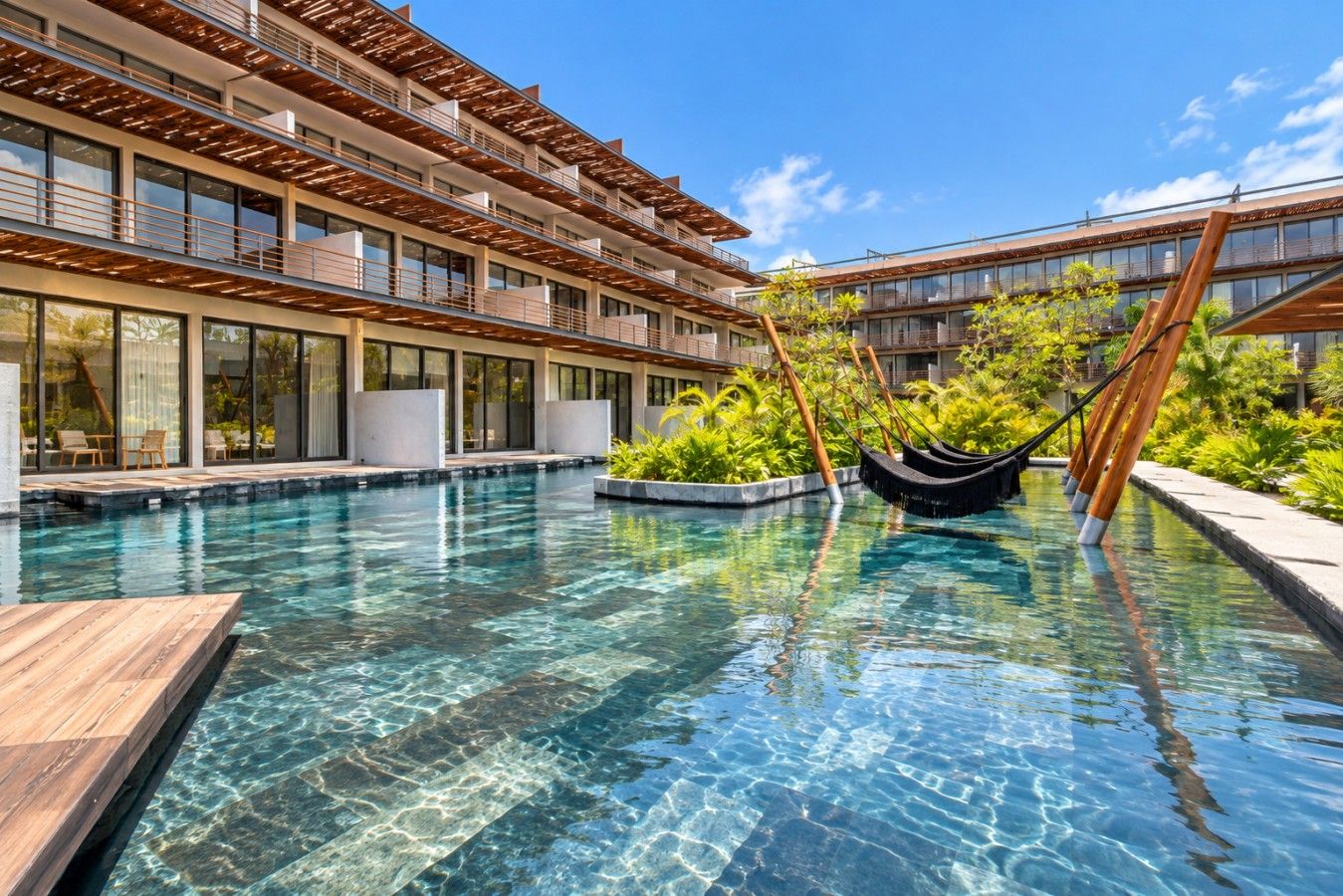 Ein Hotel mit Schwimmbad, Sitzgelegenheiten im Freien und einer Hängematte.