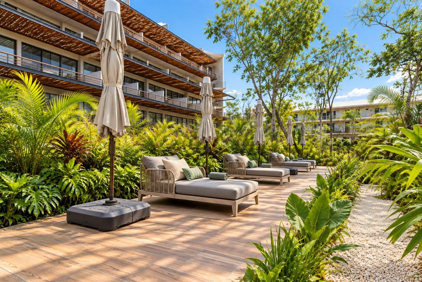 A resort with outdoor seating areas, palm trees, and a building with multiple balconies.