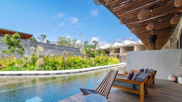 Un espace aménagé au bord de la piscine, avec des chaises longues en bois et un mur en béton.