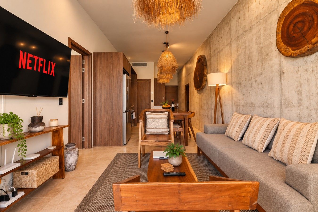 Un salon moderne doté d’un téléviseur à écran plat, de meubles en bois, d’un coin repas et d’un mur en pierre.