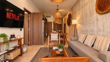Un salon moderne doté d’un téléviseur à écran plat, de meubles en bois, d’un coin repas et d’un mur en pierre.