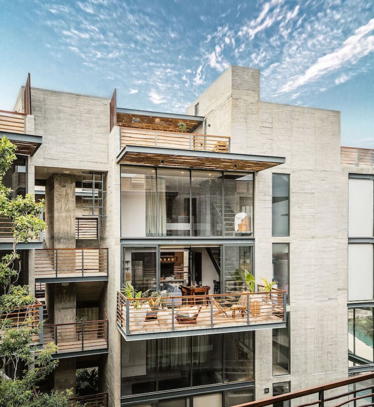 A modern multi-story building with a balcony on the second floor, large windows, and a visible staircase.