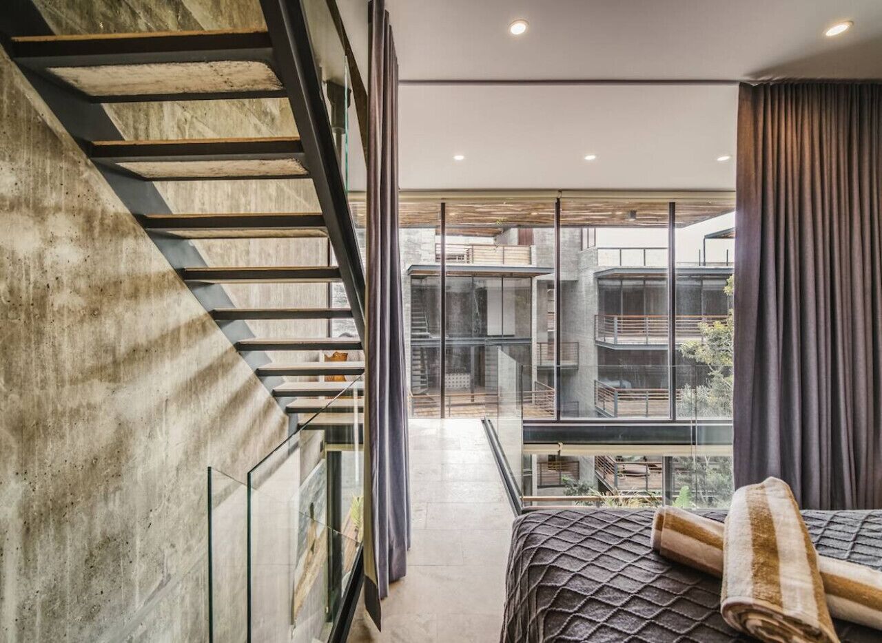 Une chambre moderne avec une grande fenêtre, un escalier et une vue sur l’extérieur.