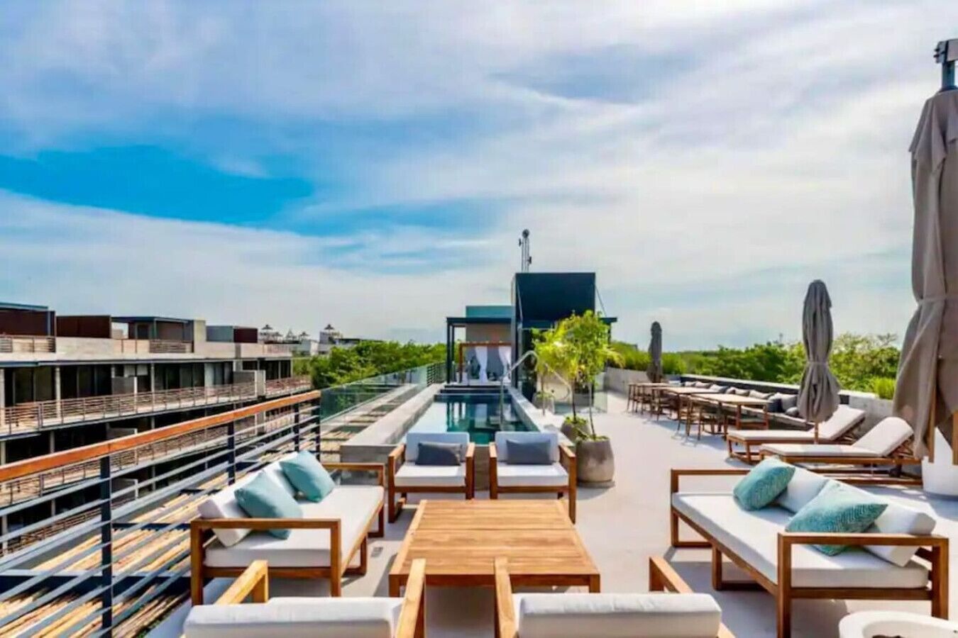 A rooftop lounge with a pool, sun loungers, and a view of the city skyline.