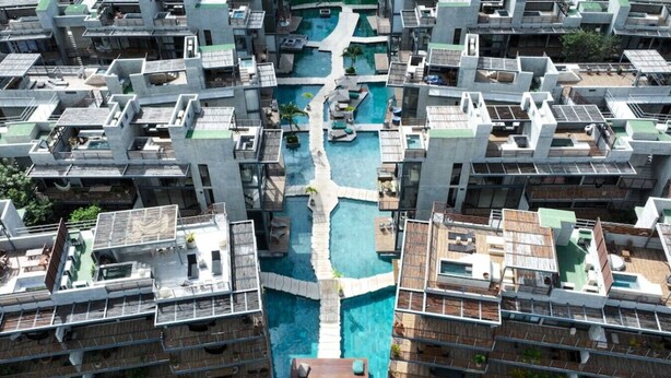 Ein Hochhaus mit mehreren Balkonen, einem zentralen Schwimmbad und einem Dachgarten.