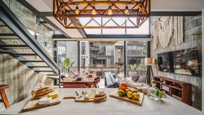 Eine moderne Küche mit einer zentralen Kochinsel, einem Essbereich mit Holztisch und einer Treppe, die in einen oberen Bereich führt.