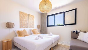 Habitación de hotel con dos camas, un sofá, un ventanal grande y una lámpara en el techo.