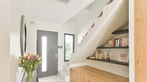 Un interior moderno con una escalera, una consola de madera y un jarrón de tulipanes.