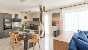 Una cocina moderna con comedor, sofá y un amplio ventanal con cortinas.