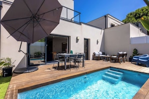A swimming pool with a wooden deck, outdoor furniture, and a large umbrella. - Maison Marly avec piscine privee a Serignan (Sérignan)