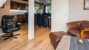 A spacious room with a wooden floor, a dining area with a table and chairs, and a kitchen in the background. - 4 Star Holiday Home in Hojer (Højer)