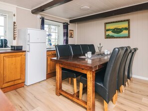 A dining area with a wooden table, black chairs, and a white refrigerator. - 4 Star Holiday Home in Hojer (Højer)