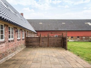 A brick building with a tiled roof and a wooden gate leading to a grassy area. - 4 Star Holiday Home in Hojer (Højer)