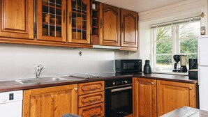 A kitchen with wooden cabinets, a microwave, a coffee maker, and a dishwasher. - 4 Star Holiday Home in Hojer (Højer)