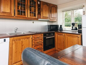 A kitchen with wooden cabinets, a microwave, a coffee maker, and a dishwasher. - 4 Star Holiday Home in Hojer (Højer)