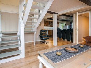 A modern interior with a staircase, a dining area with chairs, and a kitchen in the background. - 4 Star Holiday Home in Hojer (Højer)