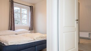 A bedroom with a bed, a window with curtains, and a white door. - 4 Star Holiday Home in Hojer (Højer)