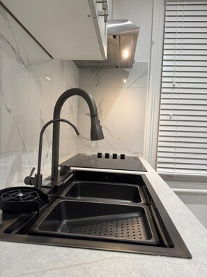 A kitchen with a stainless steel sink, a modern faucet, and a window with blinds. - Stylish 1BR and Sofa Bed Walk to London Eye 20 Mins (London)