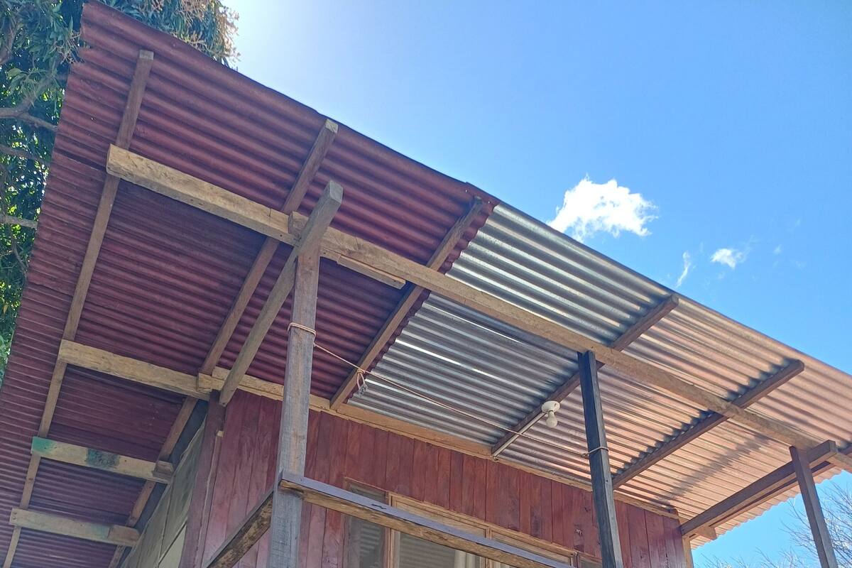 Una struttura in legno con un balcone e un tetto in lamiera ondulata.
