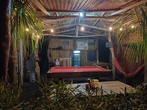 Una sala poco iluminada con una mesa de billar, una zona de bar y un tablero de menú.