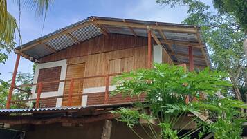 Ein Holzhaus mit Wellblechdach, einer Holzveranda und einer Hängematte.