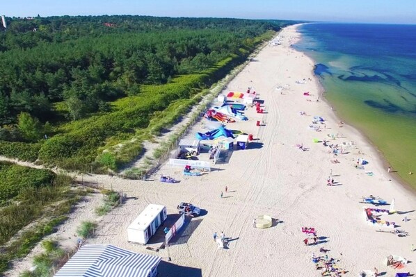 A beach with tents and beachgoers. - Apartment With a Balcony, Garden With Barbecue (Krynica Morska)