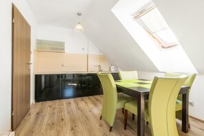 A dining area with a table and chairs, a kitchen in the background, and a skylight. - Apartment With a Balcony, Garden With Barbecue (Krynica Morska)