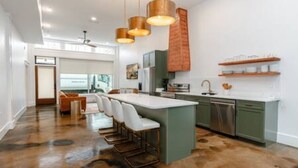 Een moderne keuken met een centraal eiland, barkrukken en hanglampen.