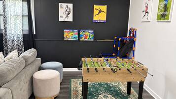 Ein Wohnzimmer mit einer Couch, einem Hocker und einem Kicker.