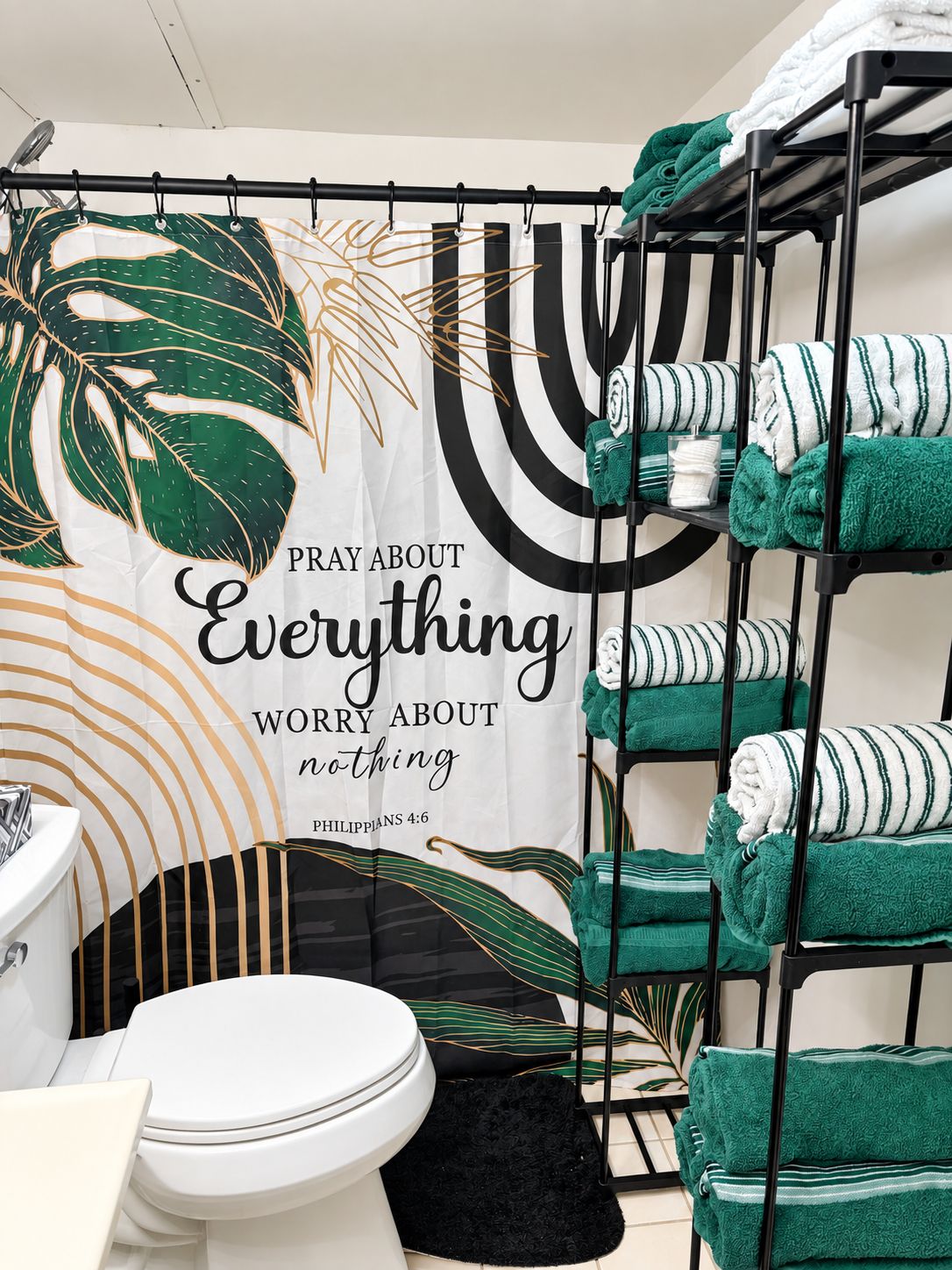 Een badkamer met toilet, wastafel en een handdoekrek met opgevouwen handdoeken.
