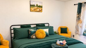 Ein Schlafzimmer mit einem Bett, zwei Stühlen, einem Bild an der Wand und einem Vorhang.