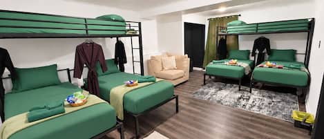 A dormitory room with bunk beds, a sofa, and a small table with items on it.