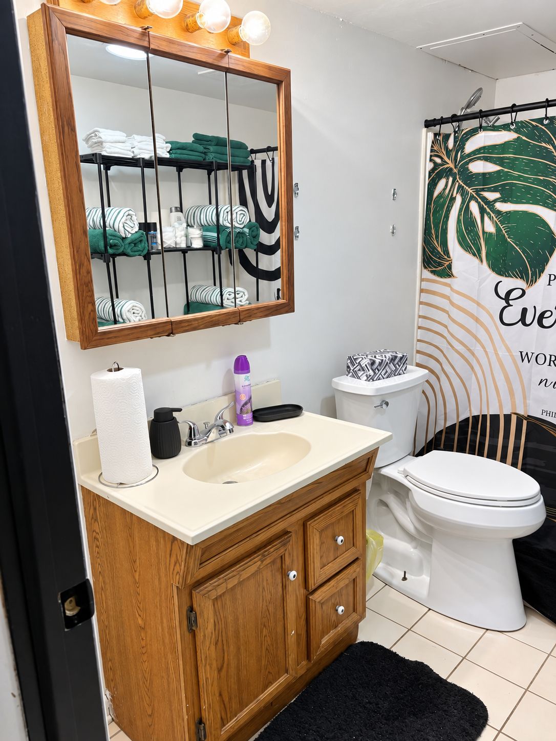 Une salle de bain avec un meuble-lavabo en bois, un évier, des toilettes et un miroir avec éclairage.