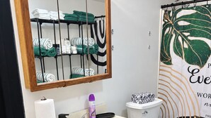 Ein Badezimmer mit einem Holzkosmetikschrank, einem Waschbecken, einer Toilette und einem Spiegel mit Beleuchtung.