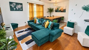 Ein modernes Wohnzimmer mit einem Ecksofa, einem Esstisch und einem Deckenventilator.