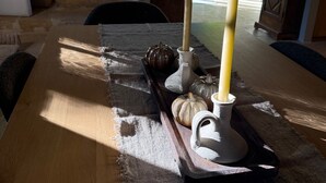Ruokapöytä, jossa on kynttilöitä, kurpitsoja ja maalaishenkinen tunnelma.