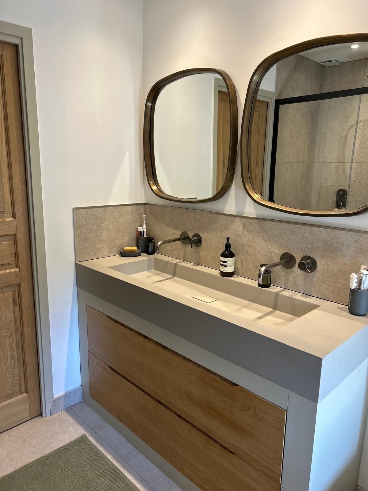 A bathroom with a double sink, wooden cabinetry, a mirror, and a towel rack.