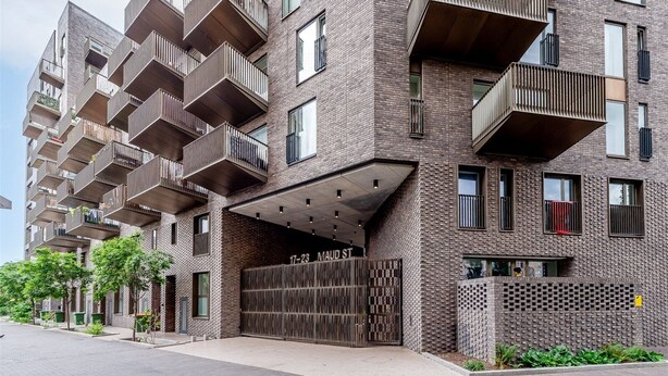 Un edificio moderno de apartamentos con varios balcones y una entrada cubierta.