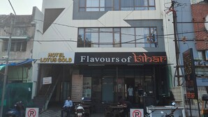 A multi-story building with a sign for Hotel Lotus Gold and a restaurant named Flavours of Bhilar. - HOTEL LOTUS GOLD (Vadodara)